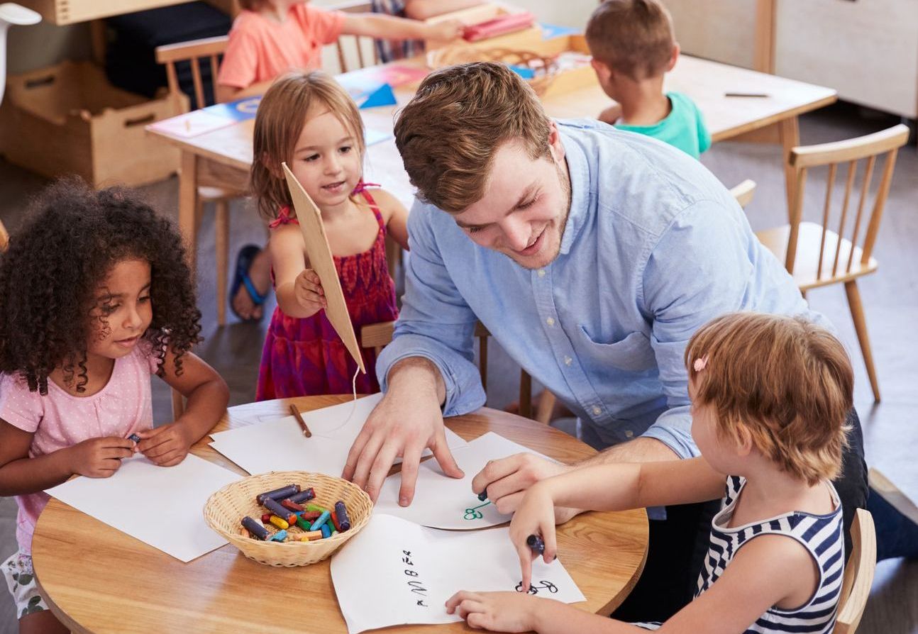 Teacher And Pupils Practicing Writing In Montessori School